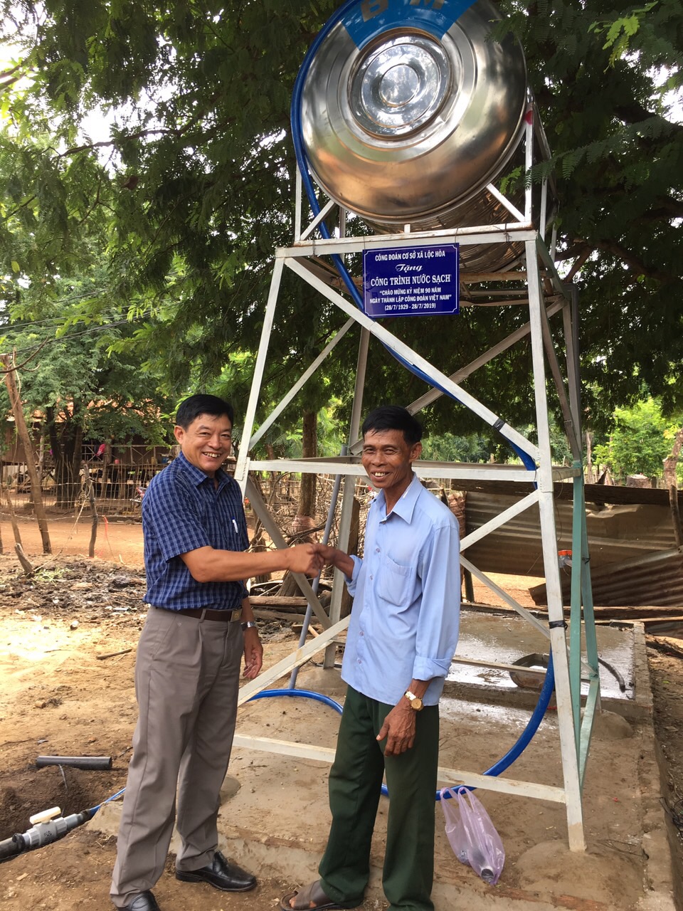 Đ/c Nguyễn Xuân Nghĩa-Chủ tịch CĐCS xã Lộc Hòa (bên trái) chúc mừng gia đình đoàn viên được nhận công trình nước sạch